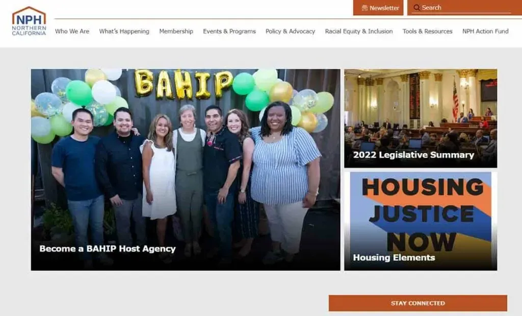 A group of people stand smiling in front of a festive backdrop with balloons and a sign that reads "BAHIP," positioned next to sections highlighting a 2022 legislative summary and housing justice information, on a website promoting community involvement.