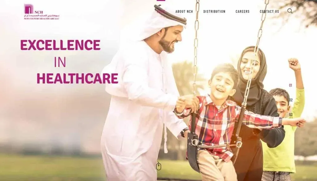 A smiling family, dressed in traditional clothing, enjoys a sunny day at the park with two children playing on swings, highlighting themes of happiness and togetherness in a healthcare setting.
