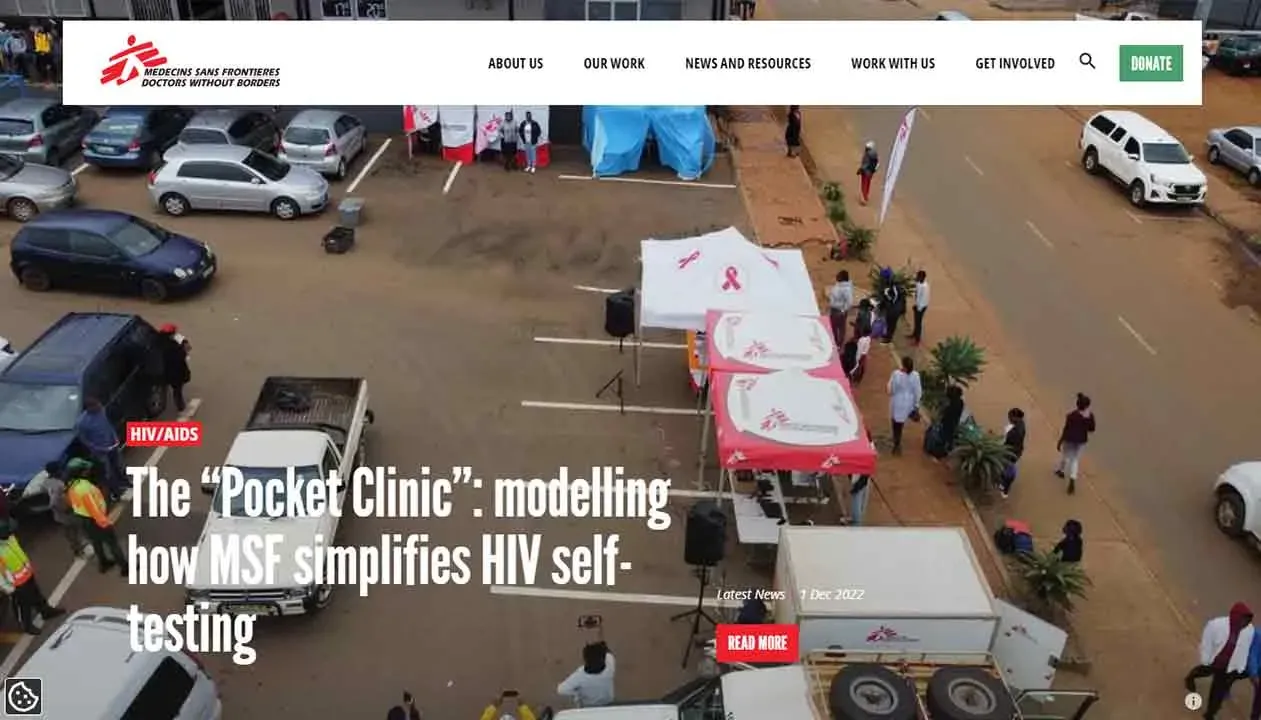 An aerial view of a street setup for a "Pocket Clinic" event, featuring medical tents and vehicles, with people gathered around for HIV self-testing services.