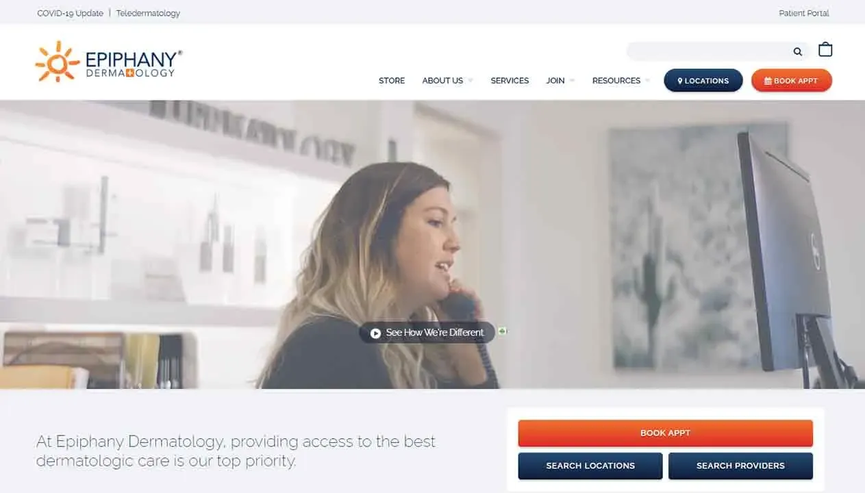 A woman is sitting at a desk, speaking on a phone while looking at a computer screen, in a modern dermatology office with artwork on the wall, emphasizing professional skincare services.