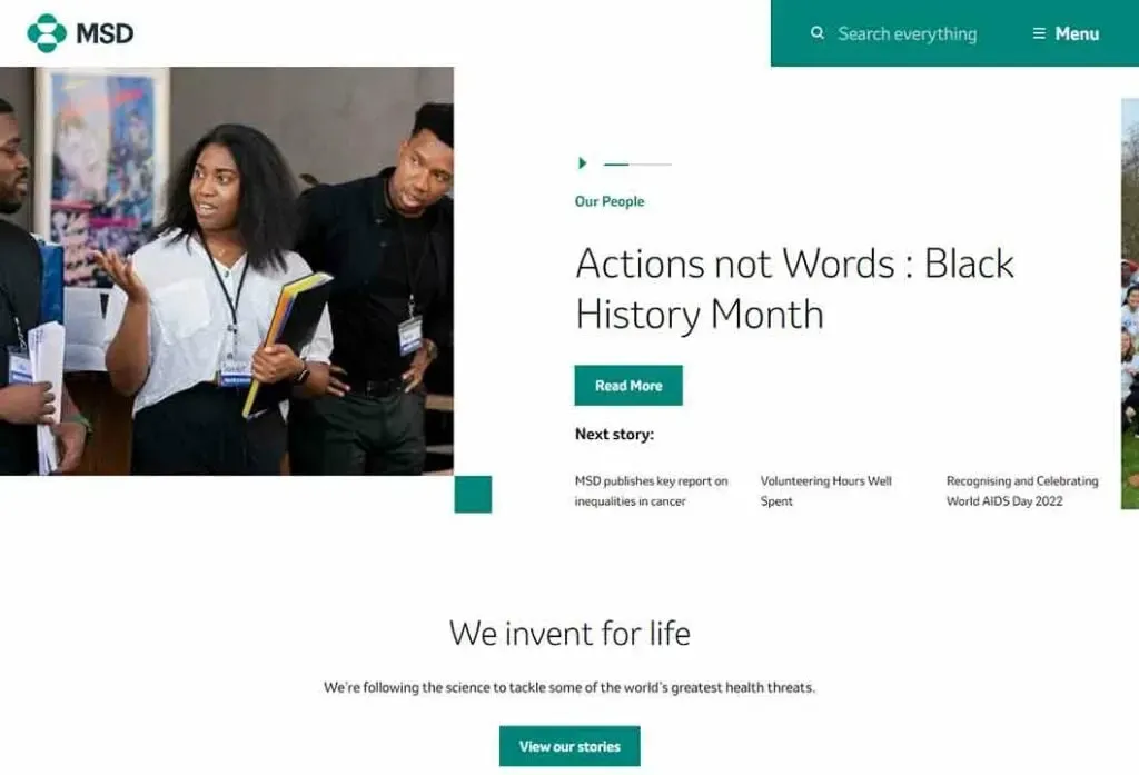 A woman stands holding papers, engaging with a group during a presentation in an MSD office, highlighting their commitment to celebrating Black History Month through the "Actions not Words" theme.