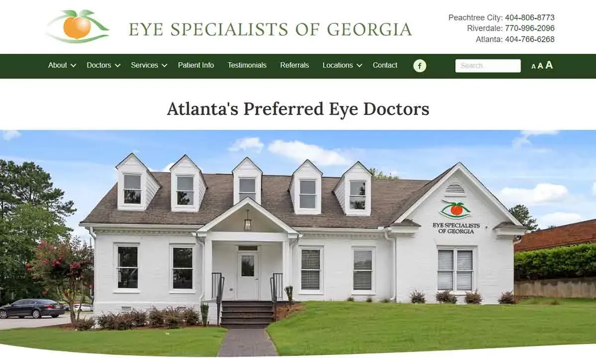 White colonial-style building with multiple dormer windows and a sign that reads "Eye Specialists of Georgia," surrounded by green lawn and clear blue sky, highlighting Atlanta’s preferred eye doctors.