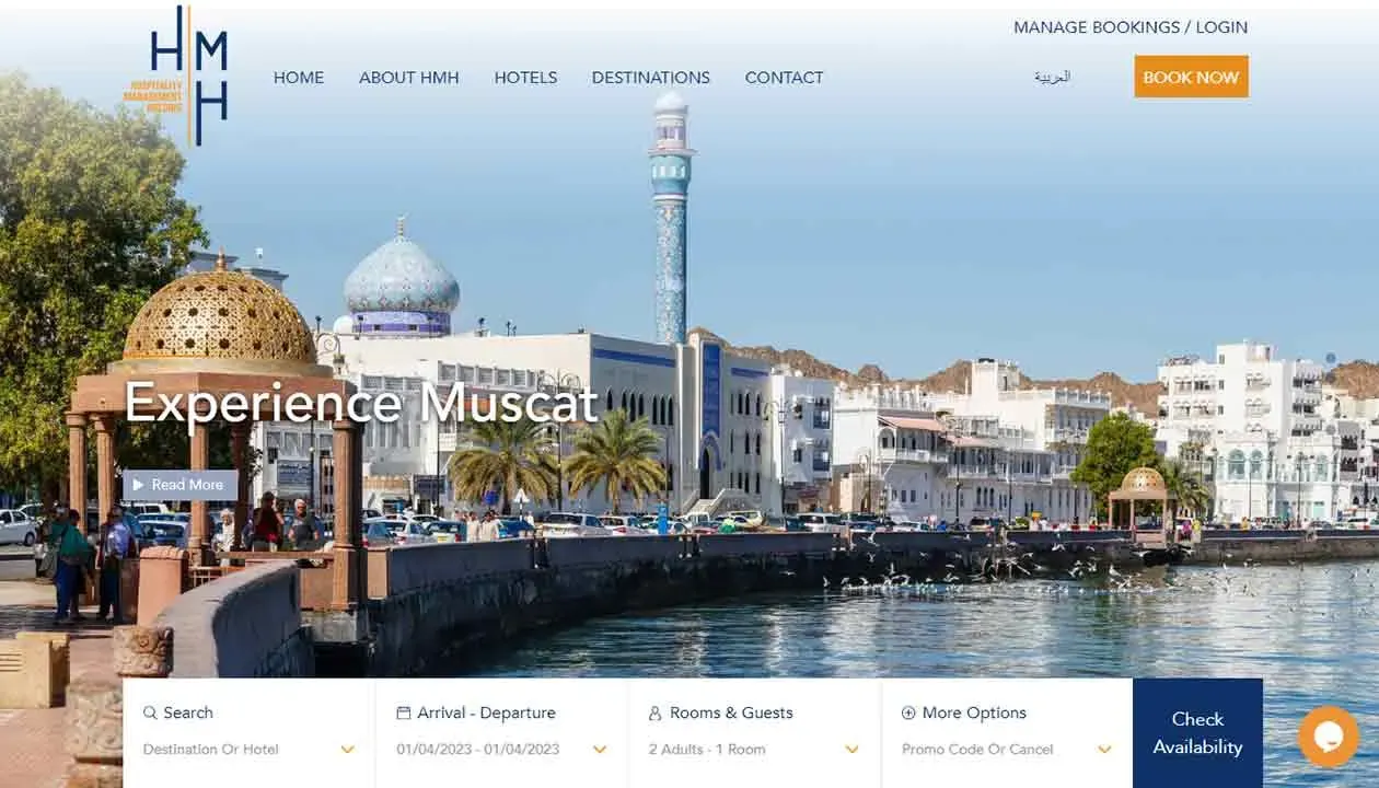 A scenic waterfront view of Muscat featuring traditional Omani architecture, a tall minaret, and elegant domed structures, with a clear blue sky and a tranquil shoreline, ideal for travel and tourism exploration.