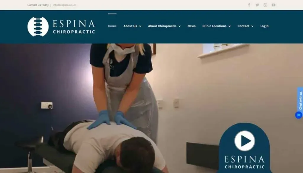A chiropractor wearing gloves and a mask is performing an adjustment on a patient lying face down on a treatment table in a clinic setting.