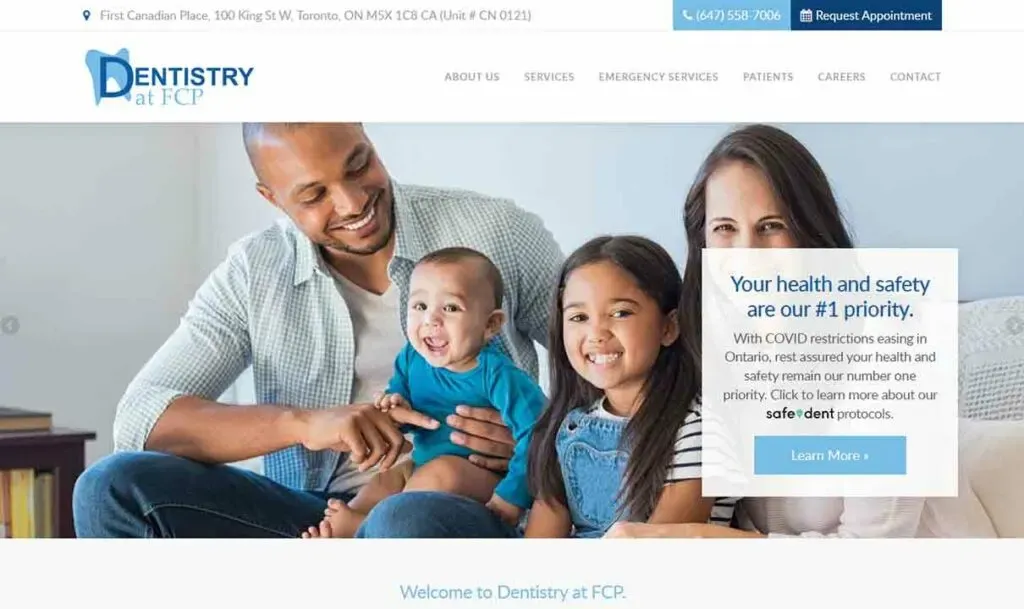 A smiling family of four, including a man, woman, young girl, and baby, sits together in a welcoming dental office, promoting health and safety protocols.