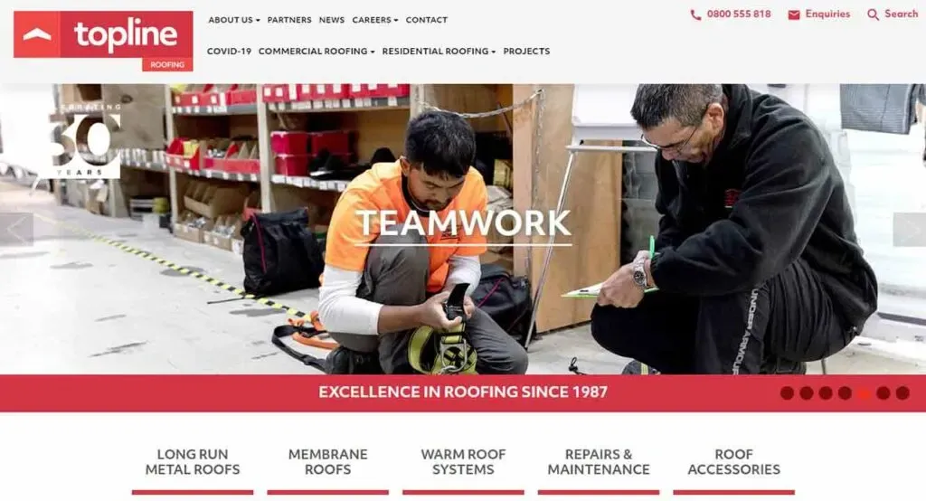 Two men work together diligently in a well-organized warehouse, surrounded by shelves of roofing supplies, illustrating teamwork in a professional roofing environment.