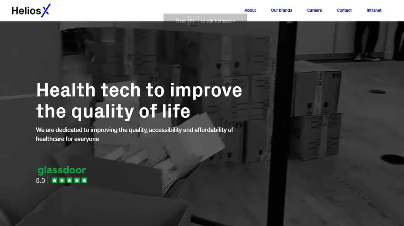 Black and white image of an office space with stacks of cardboard boxes, featuring text that reads "Health tech to improve the quality of life" highlighting a commitment to accessible and affordable healthcare solutions.