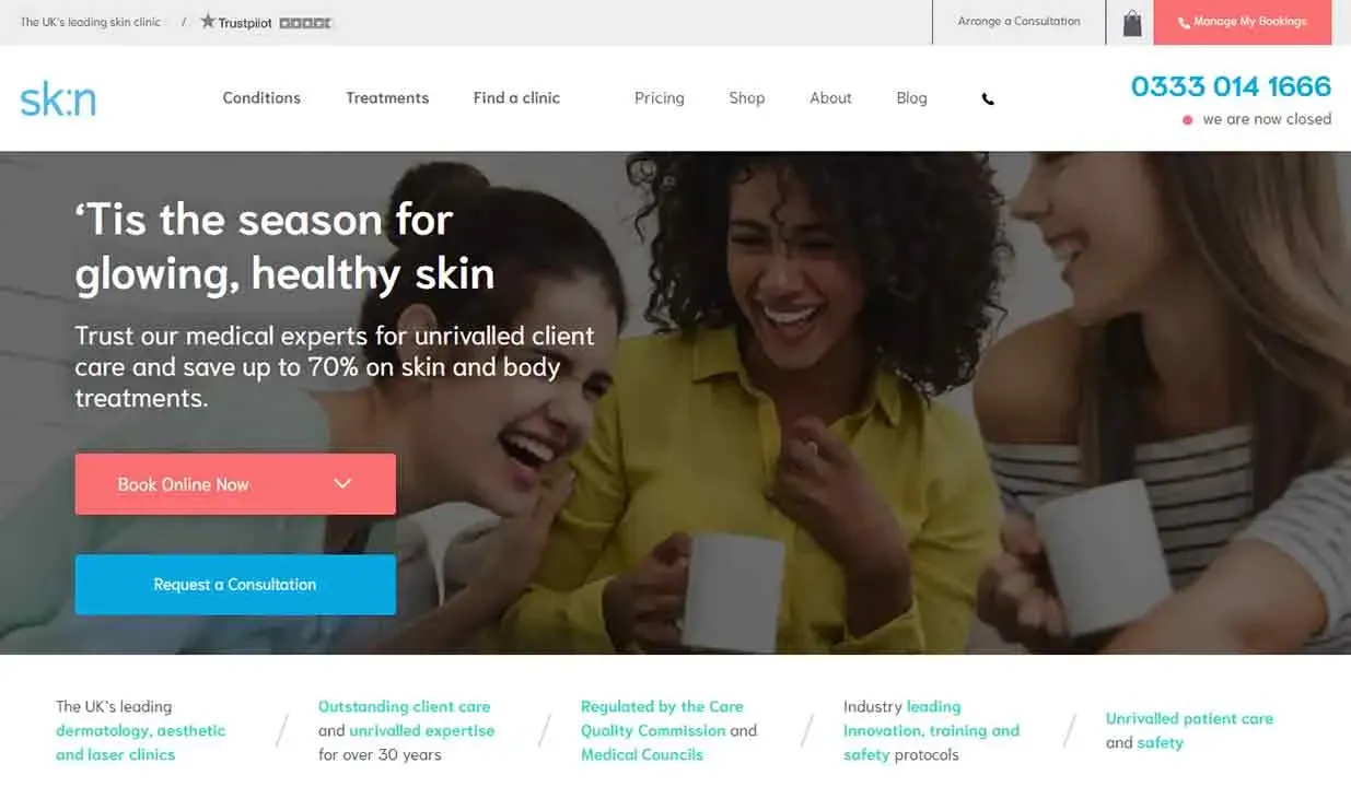 Two cheerful women and a man enjoying a lively conversation over coffee, symbolizing the joyful experience of a skincare consultation, with a website banner encouraging online booking for skin and body treatments.