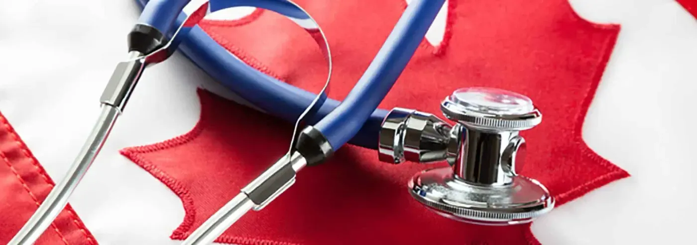 Un estetoscopio azul yace sobre una bandera canadiense, simbolizando el sector salud en Canadá, con la hoja de arce roja destacada.