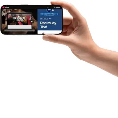 A hand holding a smartphone showing a website review video