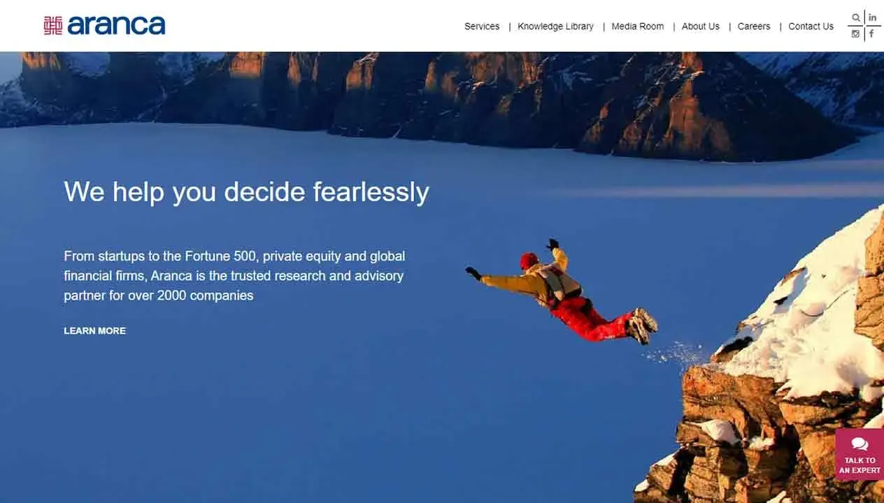A person in winter gear is captured mid-air while jumping off a snow-covered cliff, set against a backdrop of rugged mountains and a vast, frozen lake, with the text "We help you decide fearlessly" suggesting adventure and confidence.