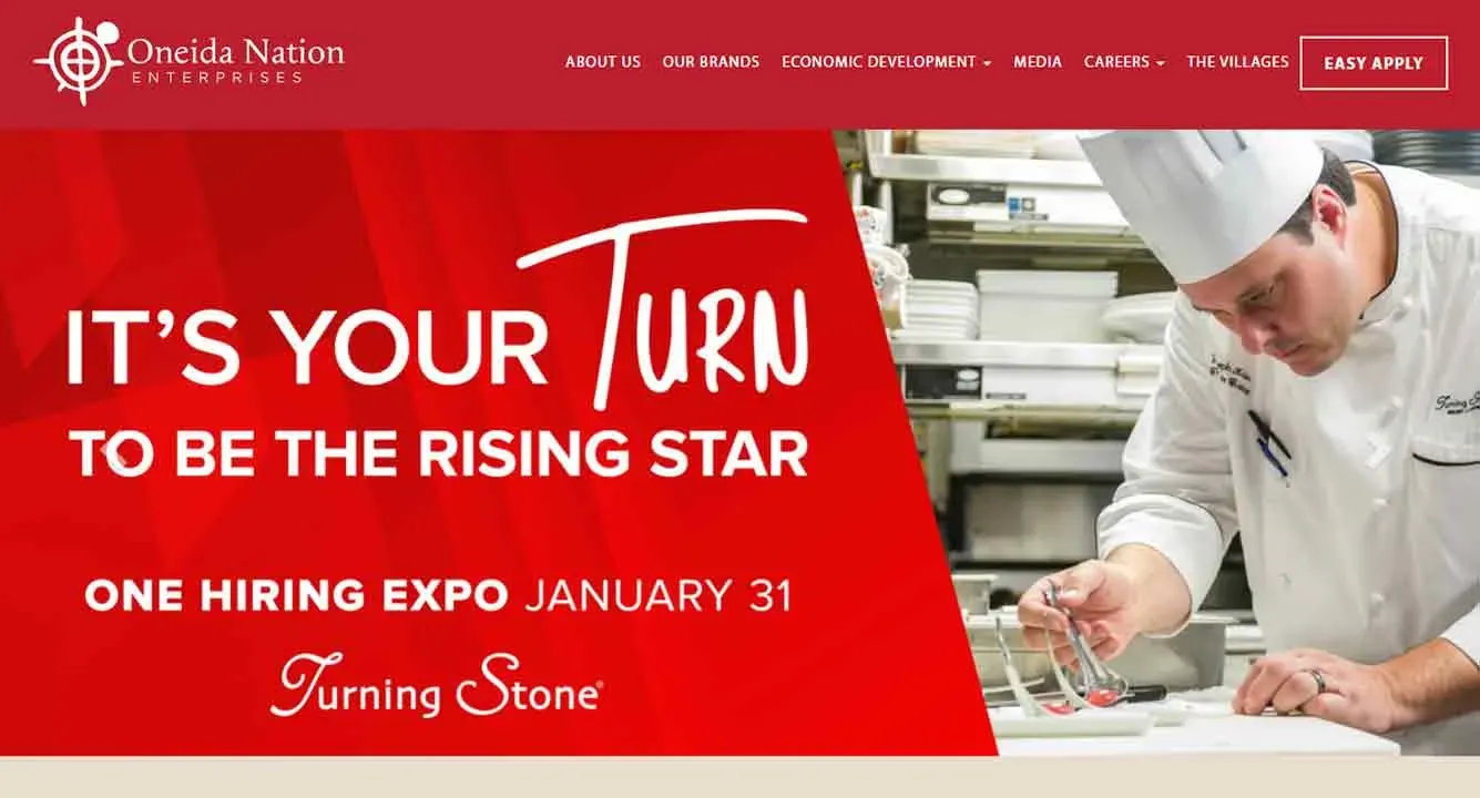 A chef meticulously arranges food on a plate in a commercial kitchen, highlighting a promotional banner for a hiring expo at Turning Stone on January 31.
