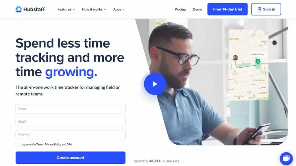 The image shows a man sitting at a desk, looking at his smartphone, with a decorative sign-up form overlay offering a free 14-day trial of Hubstaff, a work time tracker for managing field or remote teams.