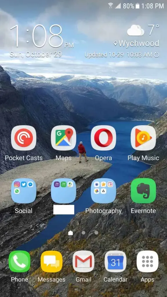 Pantalla de inicio de Android desordenada llena de carpetas de aplicaciones sobre un fondo de fiordo
