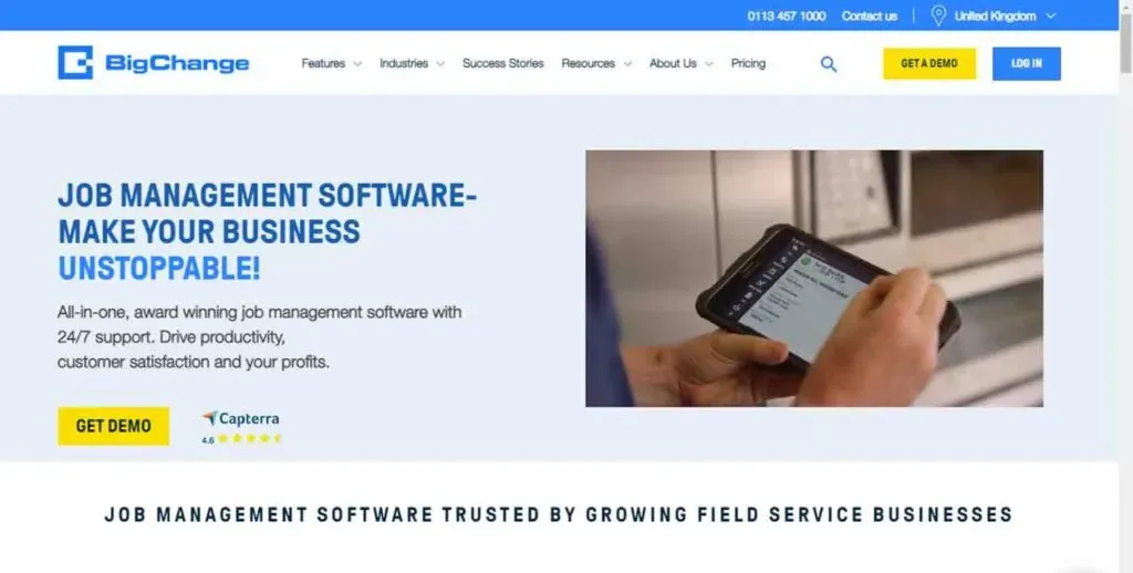 The image shows a website homepage for job management software, featuring a user holding a digital device with job details displayed, and emphasizing productivity and customer satisfaction with options for a demo and Capterra ratings.