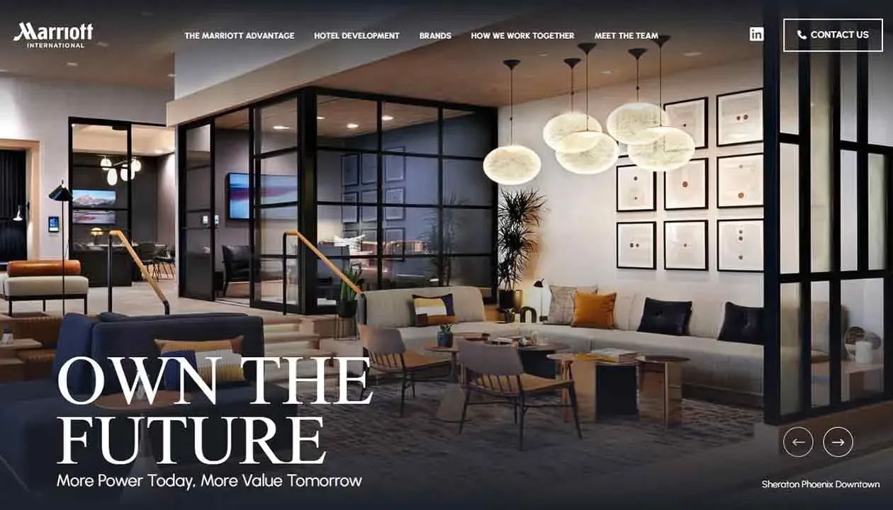 Luxurious hotel lobby with modern furnishings, featuring a spacious seating area with a large sectional sofa, contemporary hanging lights, a collection of framed art on the wall, and a sleek design, embodying the essence of sophistication and comfort.