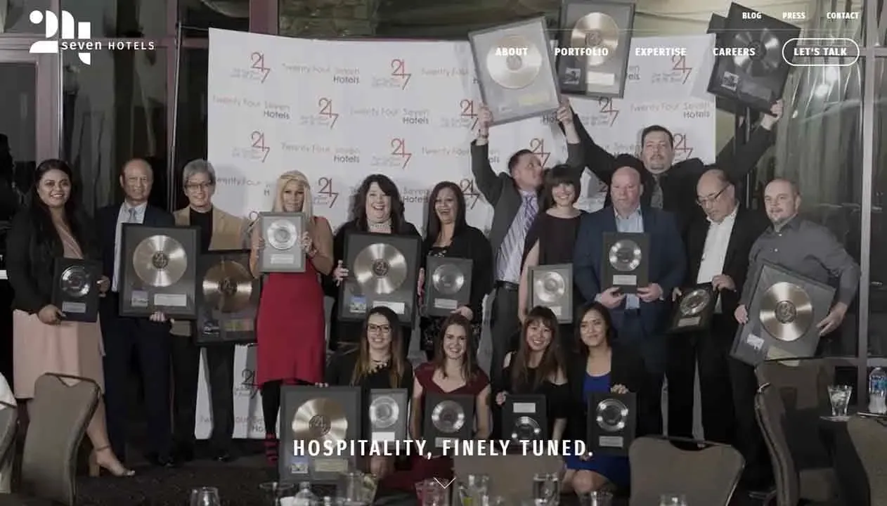 A group of people proudly holding numerous framed platinum records, standing in a hotel setting, representing a celebration or achievement event in the hospitality industry.
