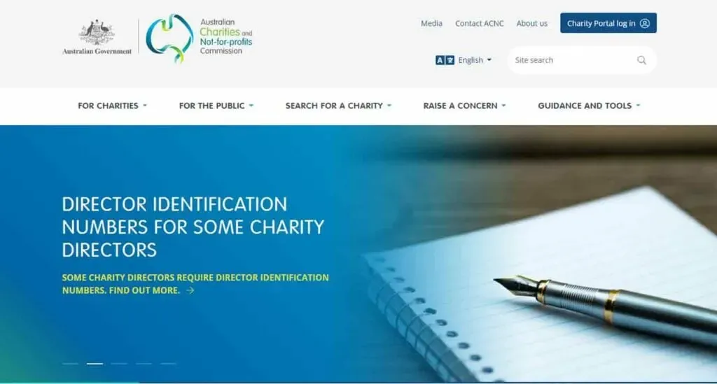 The image shows the homepage of the Australian Charities and Not-for-profits Commission website, featuring a pen resting on a notepad against a blue background with text about director identification numbers for charity directors.
