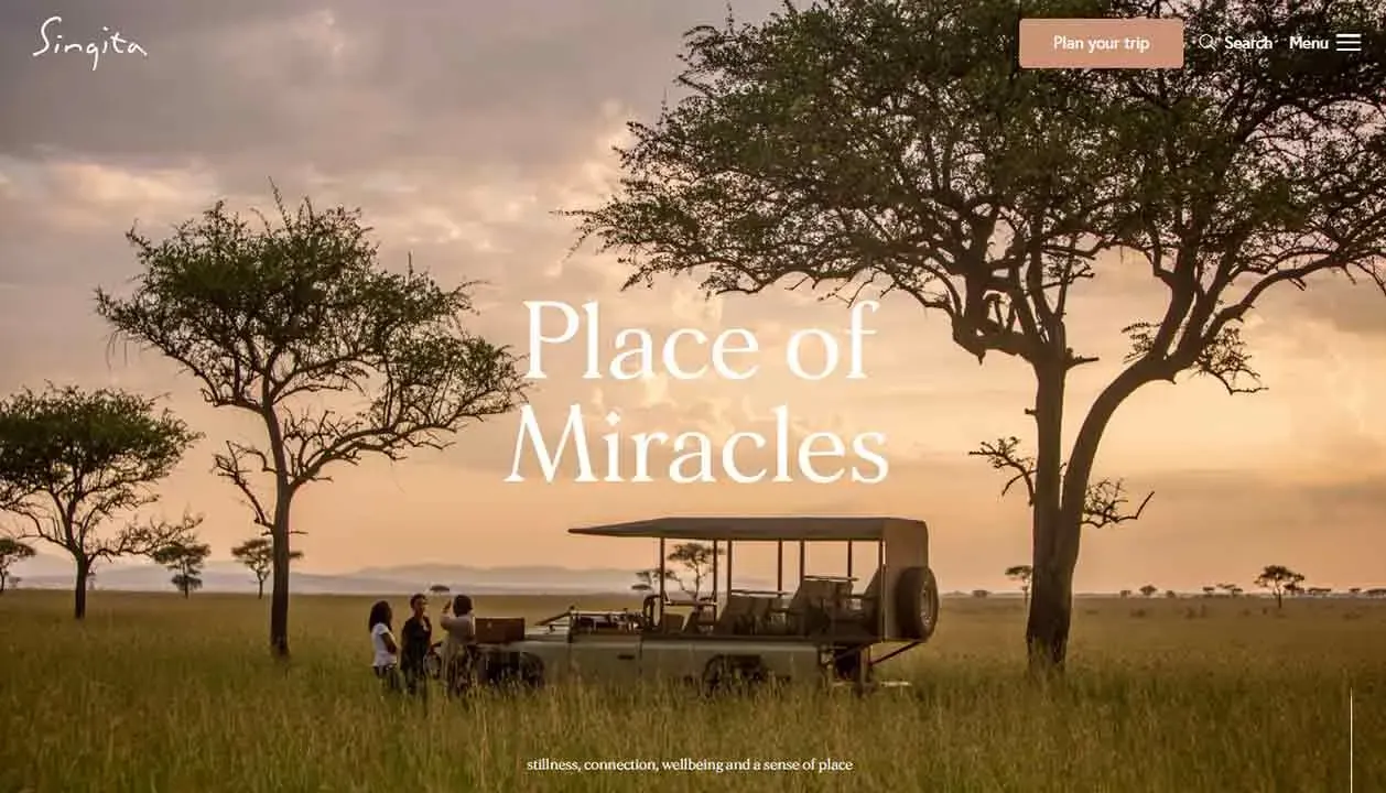 Three people stand beside an open-top safari vehicle in a vast savanna landscape with tall grasses and sporadic acacia trees under a dramatic sky, highlighting a tranquil outdoor adventure setting.