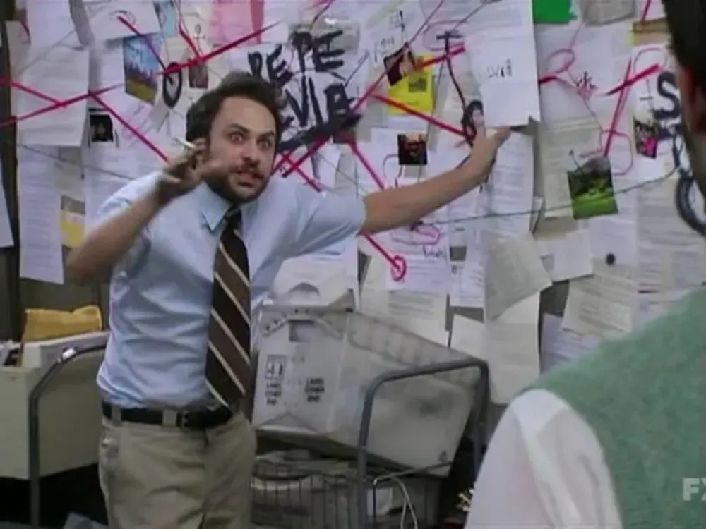 Charlie de It's Always Sunny explicando frenéticamente un muro de conspiración con papeles e hilos rojos