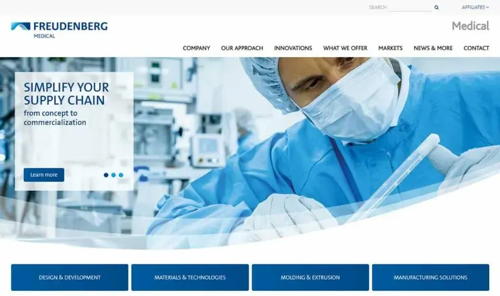 A medical professional in sterile blue scrubs and a mask closely examines a medical device in a laboratory setting, emphasizing supply chain innovation and development.