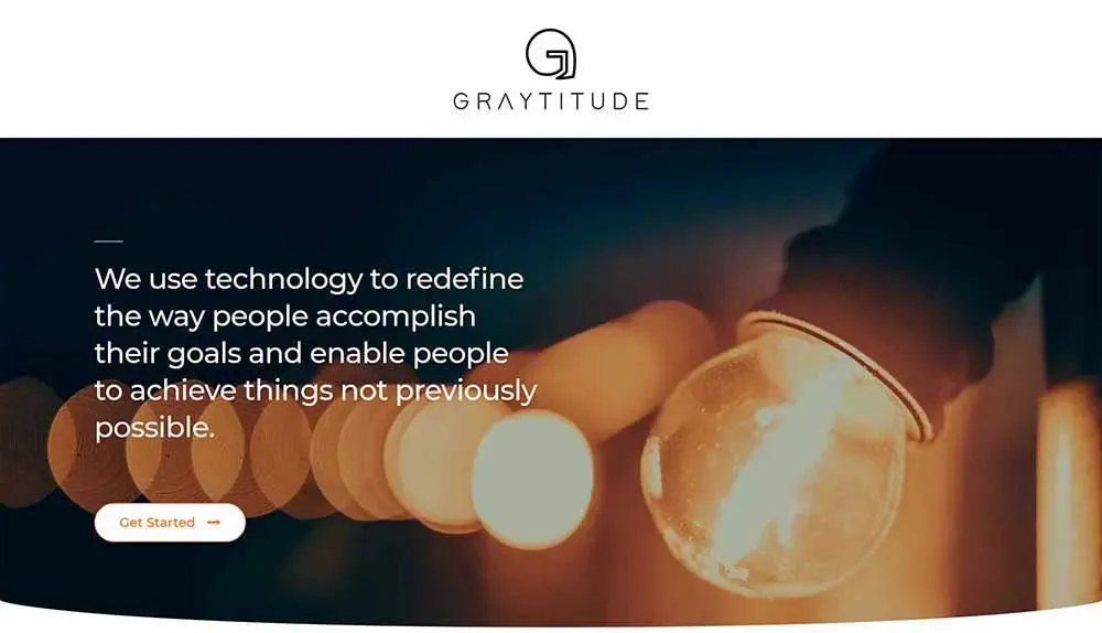 The image shows a close-up of a glowing light bulb against a blurred background with the text, "We use technology to redefine the way people accomplish their goals and enable people to achieve things not previously possible," and features a "Get Started" button, under the brand logo and name "Graytitude".