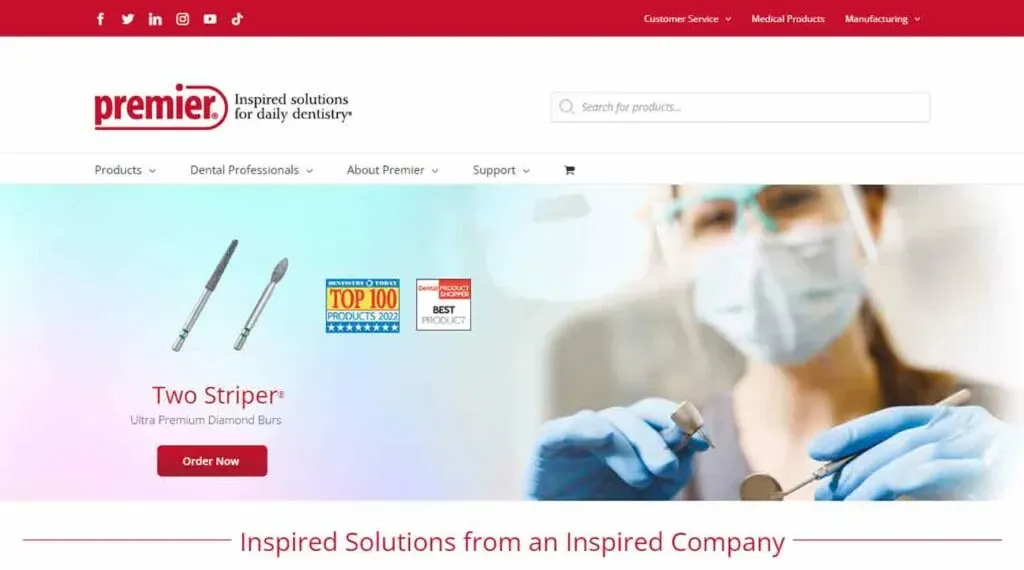 The image depicts the homepage of a dental product website, featuring a banner with a dentist in blue gloves holding a dental tool, alongside promotional text for "Two Striper Ultra Premium Diamond Burs," highlighted awards, and a prominent "Order Now" button.