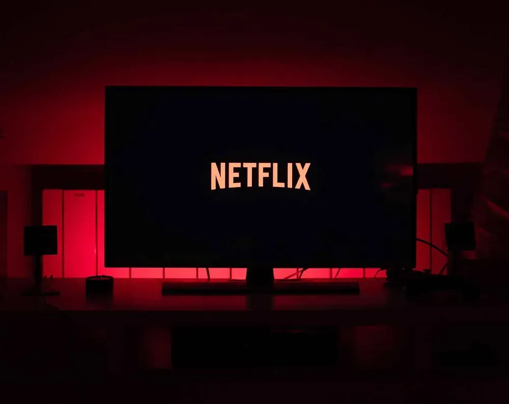 Televisor montado en la pared que muestra el logo de Netflix en una habitación oscura iluminada por retroiluminación LED roja