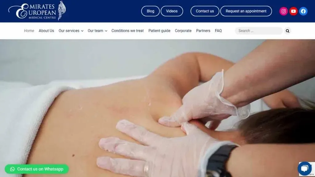 A person receiving a therapeutic massage on their back at a medical center, with a therapist wearing gloves for hygiene; the setting is designed for relaxation and healing.