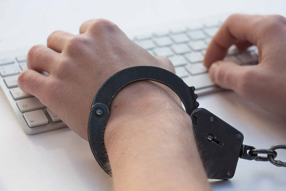 Manos esposadas a una computadora portátil simbolizando empleadores restrictivos