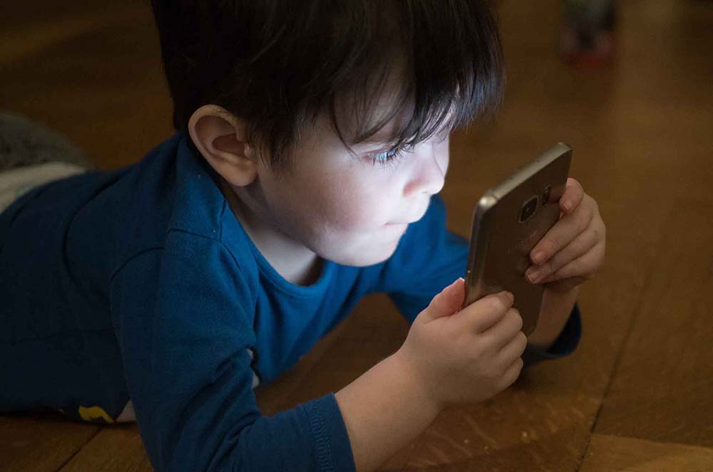 Niño mirando un smartphone, ignorando el entorno